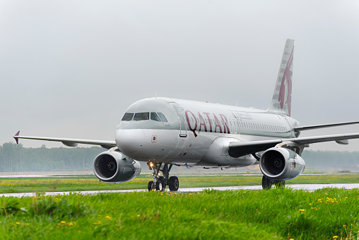 \nMoscow, Russia - May 19, 2016: Qatar airlines Airbus A320 taxiing. Plane makes taxiing on taxiway Domodedovo International Airport. Rainy and cloudy day.