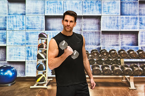 istock Muscular man exercising with dumbbells in gym 533068336