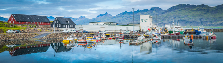 Djupivogur, Iceland - September 24, 2015: Colourful trawlers and boats in the tranquil harbour of Djupivogur, the small fishing village in the eastern fjords of Iceland. Panoramic image created from ten contemporaneous sequential photographs.