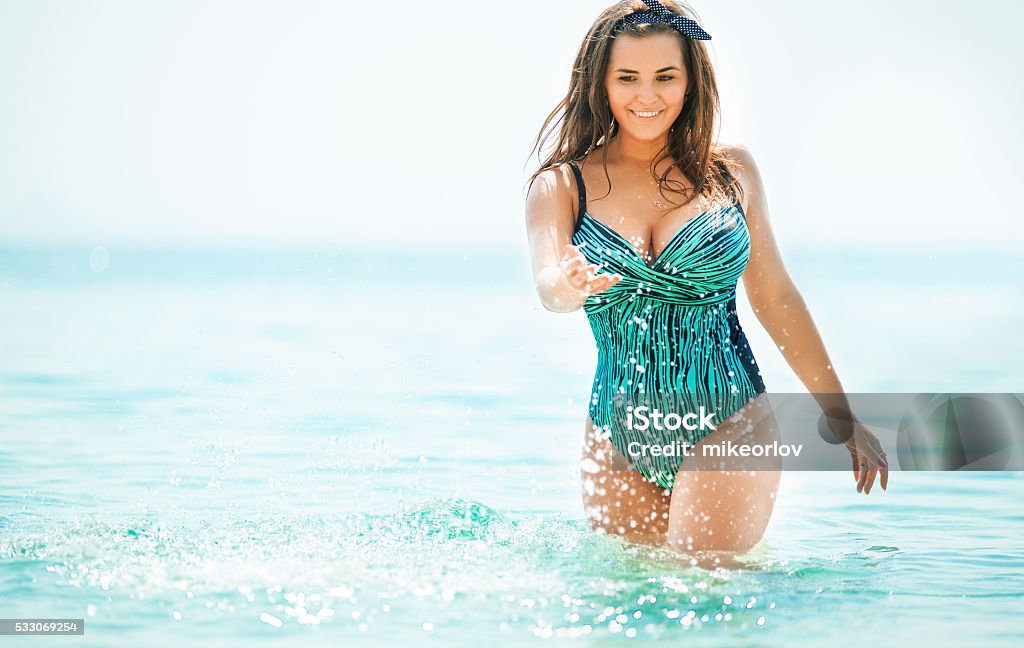 Curvy young woman in swimsuit near the sea. Size plus Woman in swimwear at the sea. Curvy young woman in swimsuit against the sea. Women Stock Photo