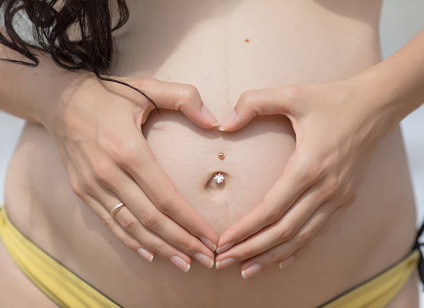 руки будущая мать на ее живот - pierced jewelry women body стоковые фото и изображения