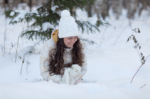 young girl lying  in snow and laugh in winter forest
