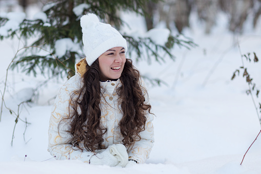 young girl lying  in snow and laugh in winter forest