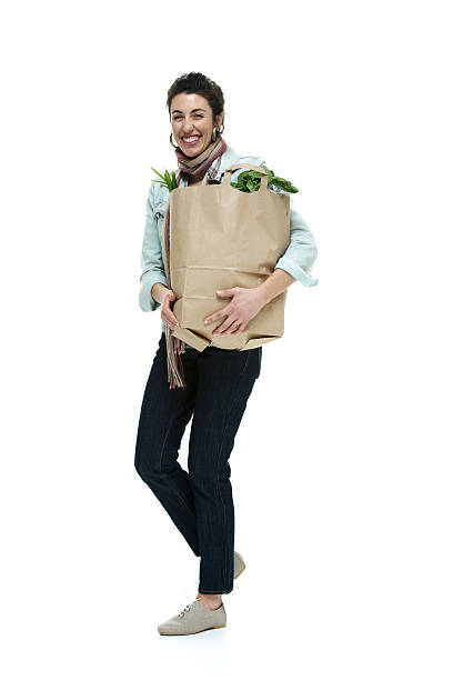 istock Cheerful woman holding vegetables bag & walking 533096189