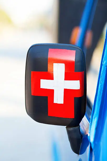 Red and white cross on sidemirror of tuk-tuk in Bangkok