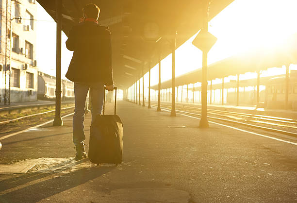 istock Man standing with bag and mobile phone at train station 533100443