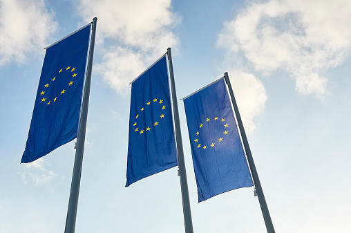 Three blue European Union flags with blue sky