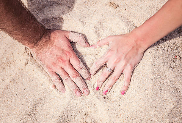 maschio e femmina mani con anelli sulla sabbia - dulcie gray foto e immagini stock