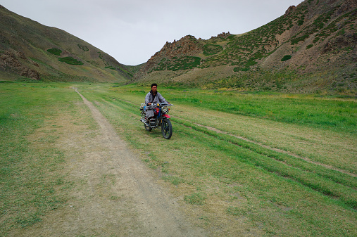 Gobi Desert, Mongolia - August 3, 2014: A mongol wrangler drives his motorbike in the Gobi Desert.