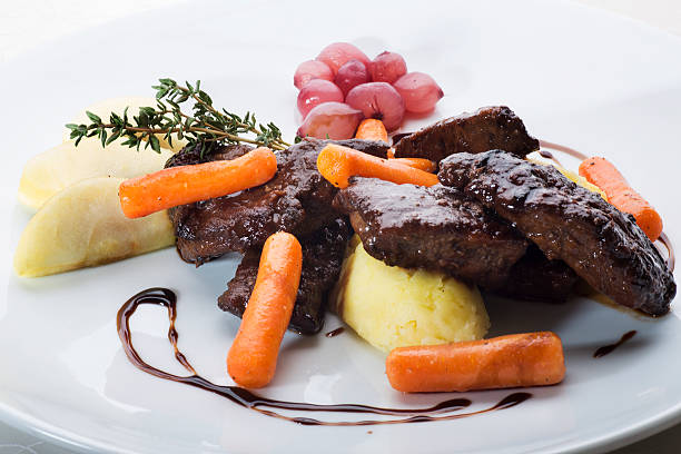 Sautéed sliced beef liver garnished with apples and baby carrots stock photo
