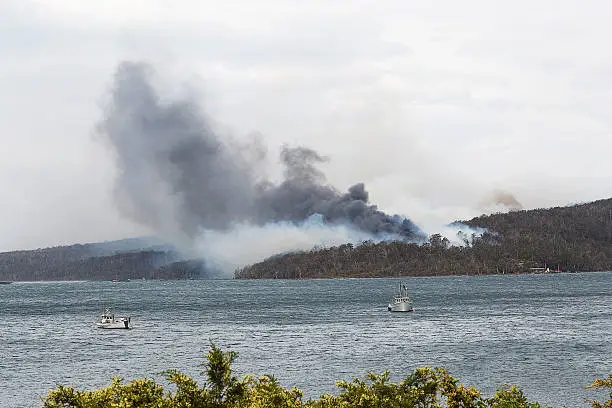 Distant view across water of a factory fire, Tasmania, Australia