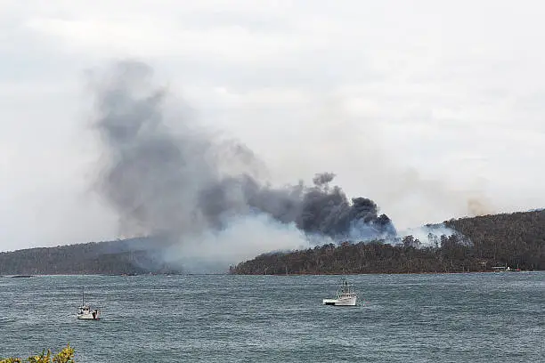 Distant view across water of a factory fire, Tasmania, Australia