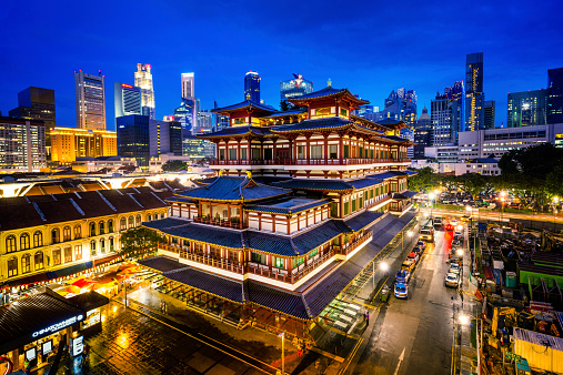 Buddha Toothe Relic Temple in Chinatown at dusk with Singapore`s business district in the background.