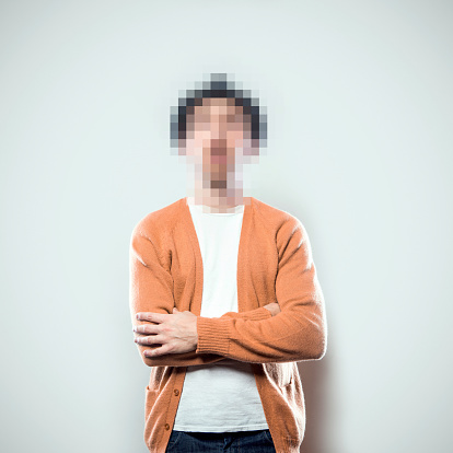 A portrait of a man from the waist up, whose face has been rendered unrecognizable by being pixelated.  A conceptual representation of individual identity protection.  Square crop with copy space on a a clean off-white background.