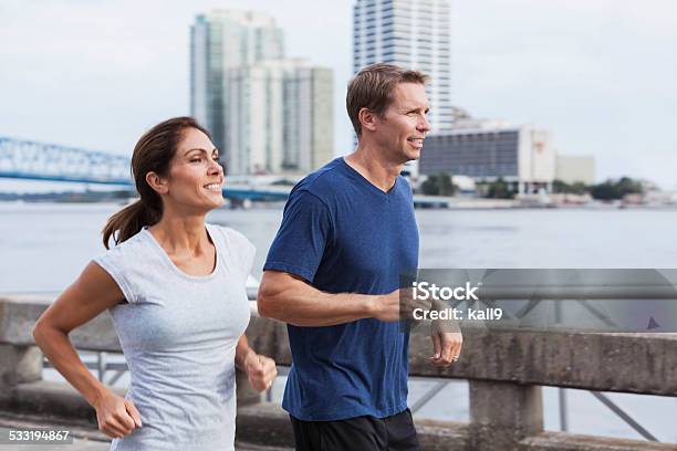 Mature Couple Jogging Together Along Waterfront Stock Photo - Download Image Now - Jogging, Couple - Relationship, 40-44 Years