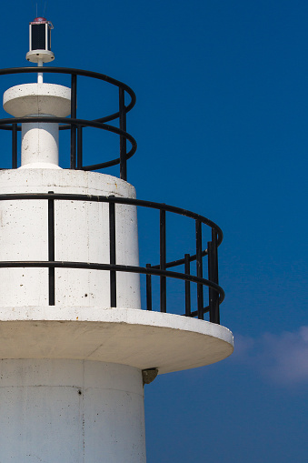 Close up view of white lighthouse on clear, blue sky.