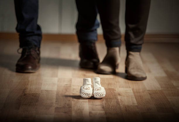 Parents waiting for a baby. Mother and father with elegant shoes and baby shoes in front of them.