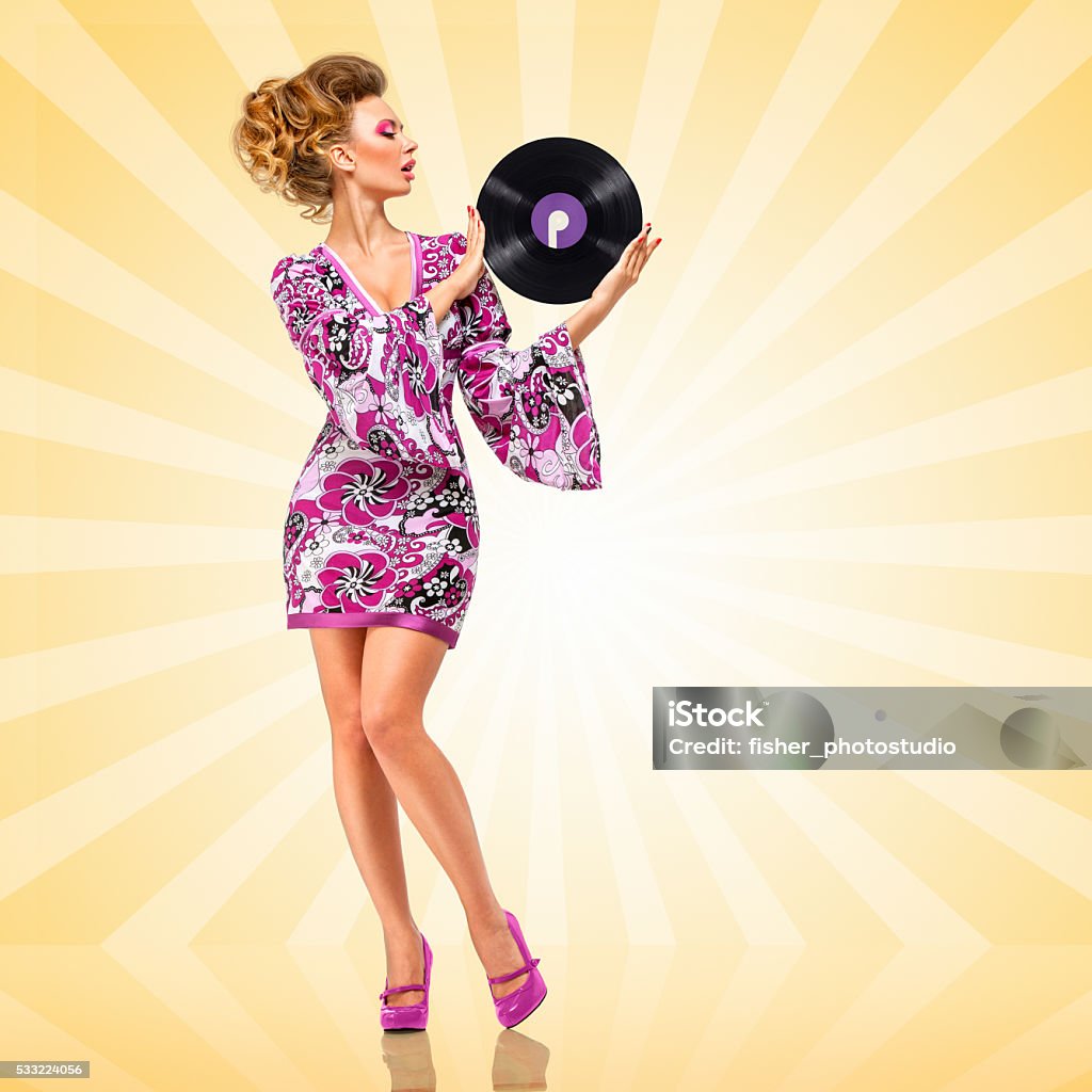 Kissing sound. Colorful photo of a clubbing fashionable hippie homemaker sending a kiss to a retro vinyl record in her hands on colorful abstract cartoon style background. 70-79 Years Stock Photo
