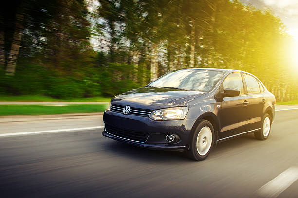 Volkswagen Polo Sedan car drive on the road at sunset stock photo