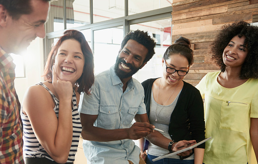 Shot of a diverse group of young designers standing with a tablet discussing work