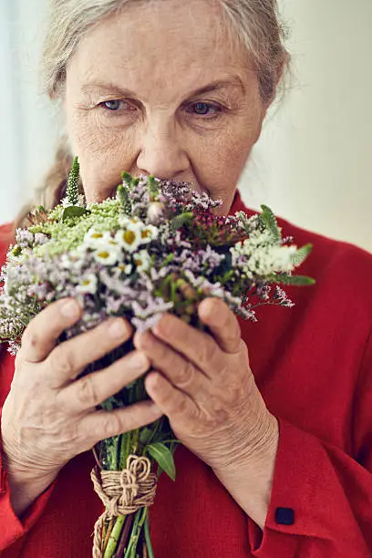 Thoughtful senior woman smelling wildflower bouquet