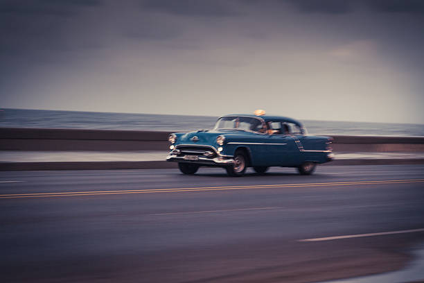 one of Havana's many classic cars drives along the city's famous seaside promenade