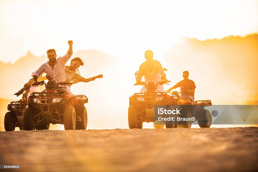 Having fun on quad bikes at sunset. Young people driving quad bikes and having fun in the desert. Quadbike Stock Photo