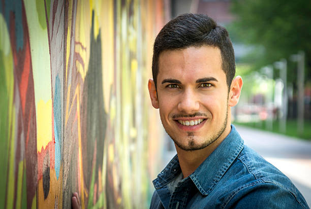 istock Smiling young man next to colorful graffiti wall 533229723