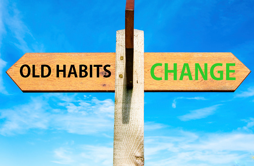 Wooden signpost with two opposite arrows over clear blue sky, Old Habits versus Change messages, Lifestyle change conceptual image