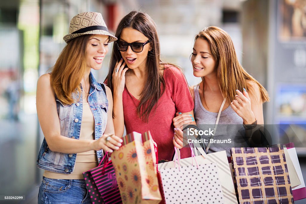 Look what I bought! Three female friends showing each other what they bought in shopping. 2015 Stock Photo