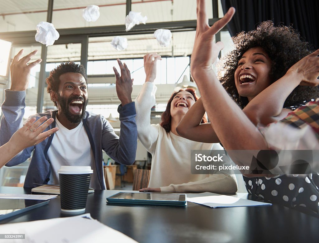Too many hours of brainstorming? Shot of a group of young business colleagues having fun throwing crumpled paper into the air Celebration Stock Photo