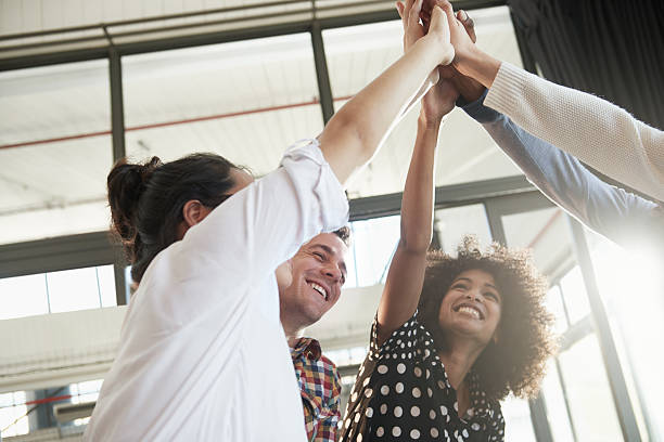 Together everyone achieves more Shot of a group of young business colleagues high-fiving each other in the office celebrate stock pictures, royalty-free photos & images