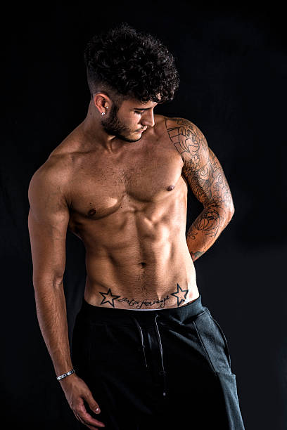 Young athletic man with tattoo isolated on black Young athletic man with tattoo posing isolated over black background, studio shot chest tattoo men stock pictures, royalty-free photos & images