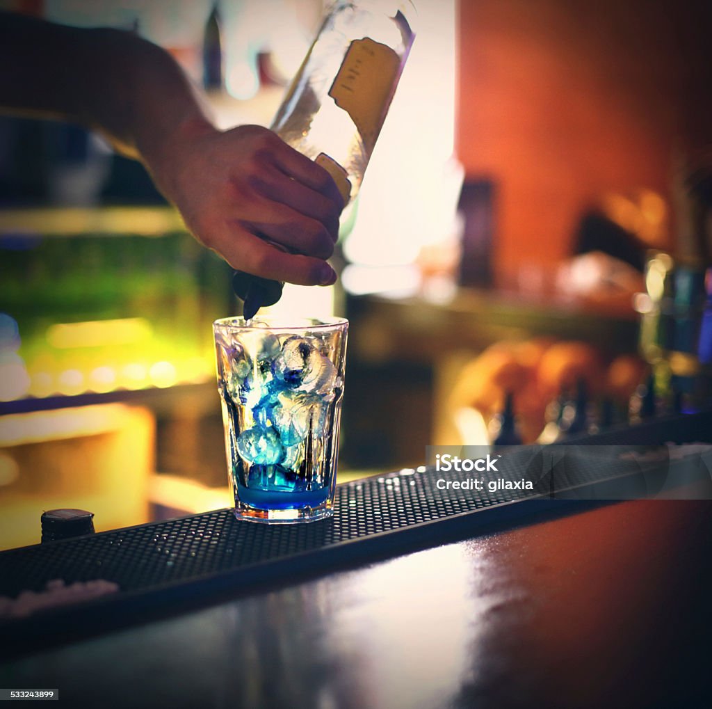 Bartender pouring drink. Closeup of professional bartender pouring drink into highball glass in order to make a cocktail. He's making blue lagoon cocktail. 2015 Stock Photo