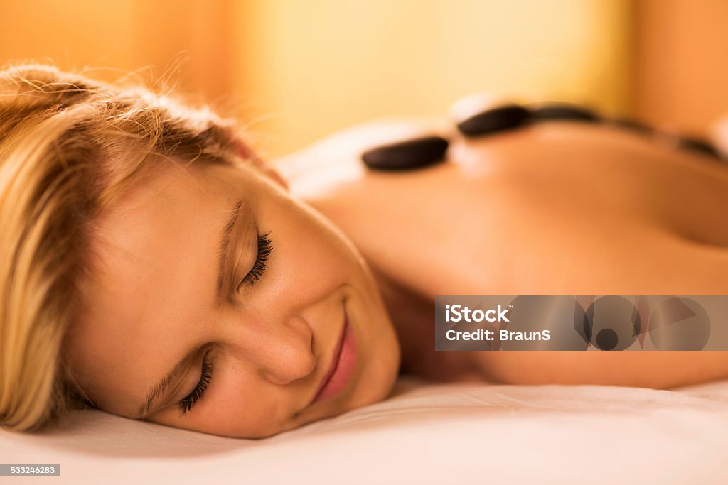 Hot stone therapy. Close up of a young woman receiving hot stone therapy in the spa. 2015 Stock Photo