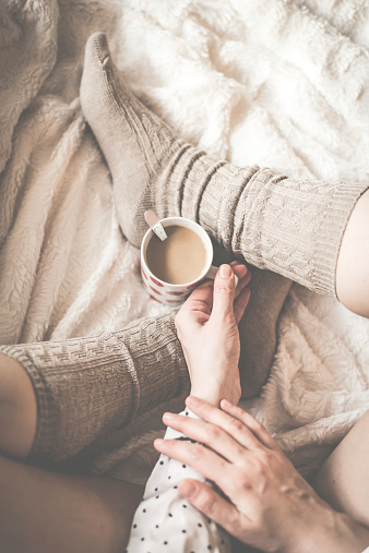 Female legs in knitted socks with cup of  coffee