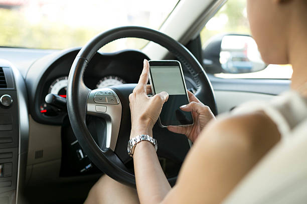 istock Woman sitting in car use mobile phone texting while driving 533252056