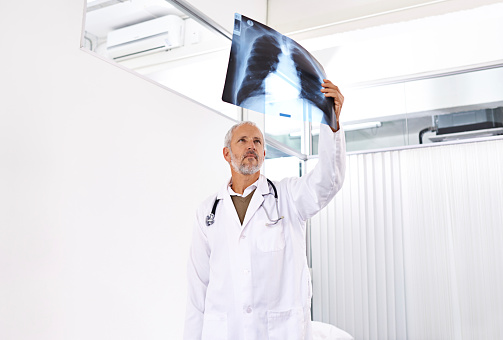 Shot of a mature male doctor examining an x-ray image at a hospital