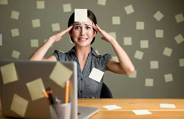 A stressed woman with post its al around her office.