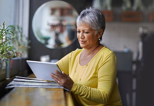 Shot of a mature woman using a digital tablet in a coffee shop