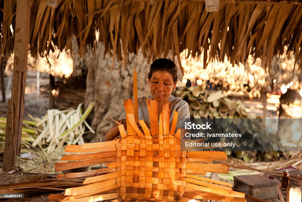 Rattan baskets in Myanmar Mandalay, Myanmar - February 28, 2011 : Middle aged Burmese woman weaving rattan baskets in a small village near Mandalay Adult Stock Photo