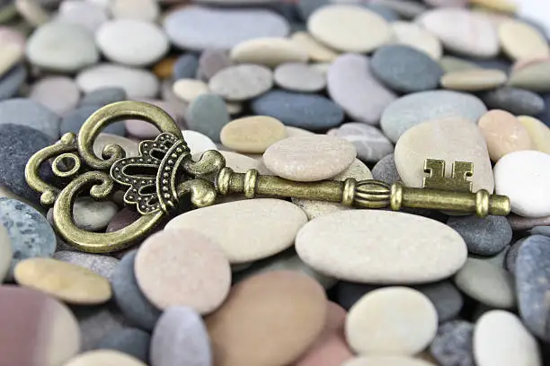 Old Brass key laing on beach stones on a pebble beach
