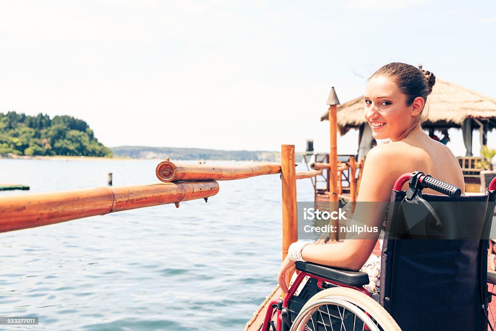 young woman in wheelchair by the sea young disabled woman sitting in wheelchair having a good time by the sea. Disability Stock Photo