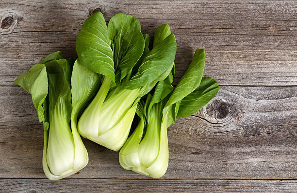 frische chinesischem kohl auf rustikal holz - chinesischer senfkohl stock-fotos und bilder