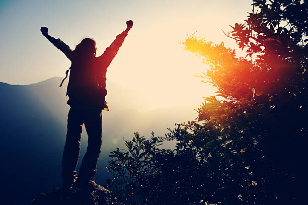 istock cheering woman hiker open arms at mountain peak 533298247