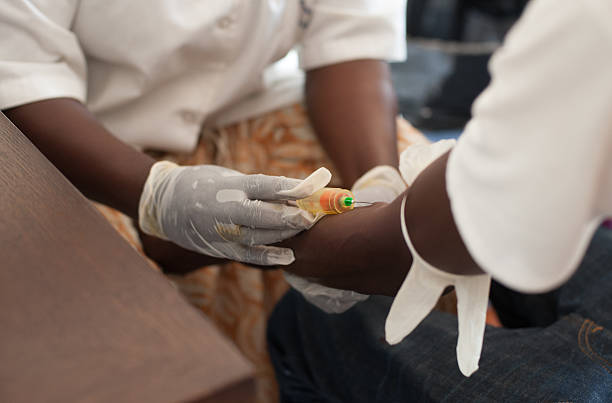 African nurse draw blood from African male African nurse with white gloves draws blood from an African man ebola stock pictures, royalty-free photos & images
