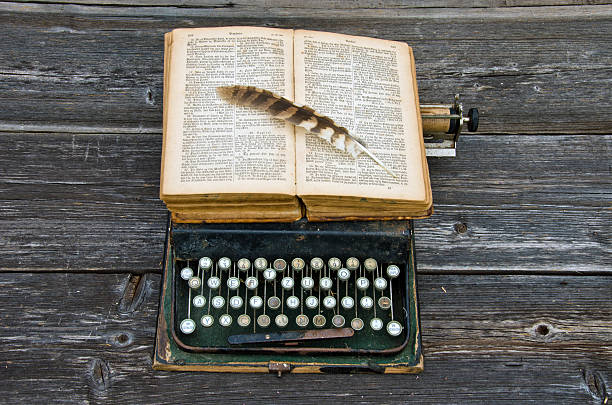 bíblia antiga máquina de escrever com livro e penas de aves no teclado - typewriter keyboard typewriter antique old fashioned - fotografias e filmes do acervo