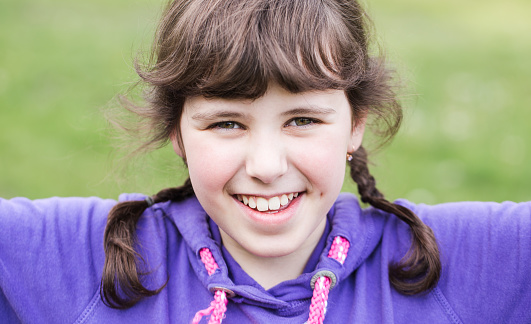 Portrait of a beautiful girl close-up. Little girl with pigtails happily spends time outdoors.