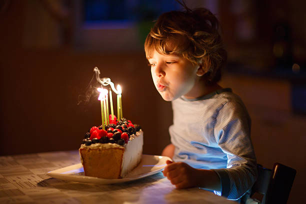 istock Little kid boy blowing candles on birthday cake 533333100