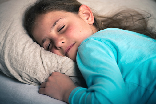 Cute young girl sleeping in bed at night.